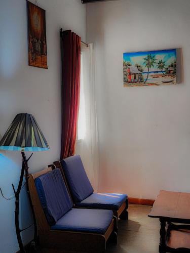 a living room with a blue chair and a lamp at La Casa Di Luna - Hotel with Pool and Restaurant in Antananarivo in Antananarivo