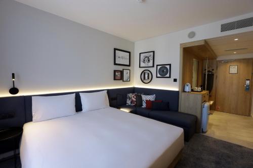 a bedroom with a large white bed and a couch at Hampton By Hilton Olsztyn in Olsztyn