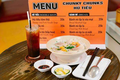 a table with a bowl of soup and a drink at Kim Thuy Hotel in Can Tho
