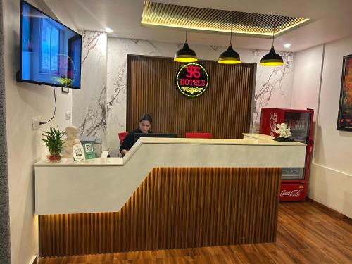 a woman sitting at a counter in a restaurant at Aliza Inn And Suites By SRS Hotels in Dharamshala