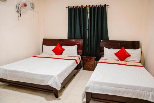 a bedroom with two beds with red pillows at Kim Thuy Hotel in Can Tho