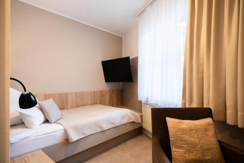 a small bedroom with a bed and a window at Hotel Lehn in Nieder-Saulheim