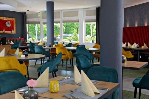 a restaurant with tables and chairs and yellow chairs at Landhotel Schnuck in Schneverdingen