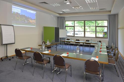 a classroom with tables and chairs and a screen at Landhotel Schnuck in Schneverdingen