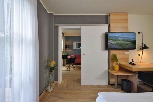 a room with a bed and a tv on a wall at Landhotel Schnuck in Schneverdingen