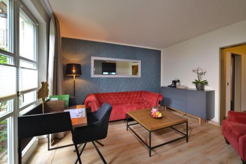 a living room with a red couch and a table at Landhotel Schnuck in Schneverdingen