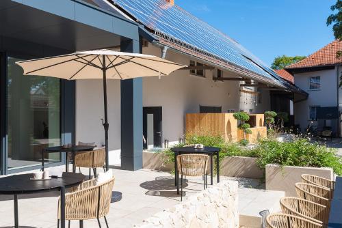 two tables and chairs with an umbrella on a patio at Hotel Lehn in Nieder-Saulheim