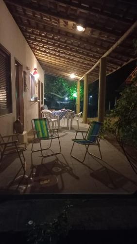a group of chairs sitting on a patio at night at CHALE PERTO DA PRAIA COM DUAS SUITES E VARANDAO in Pacatuba