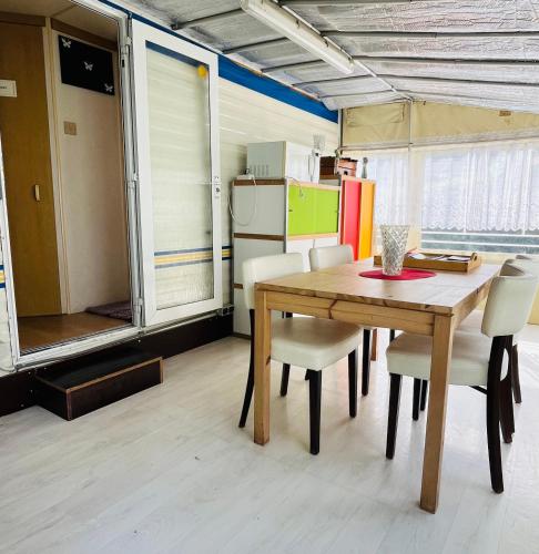 a dining room with a table and chairs and a refrigerator at Caravane en pleine nature ferme proche de tout in Philippeville