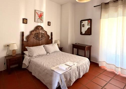 a bedroom with a large bed with a wooden headboard at Hotel Rural Palacete de Mañara in Montejaque