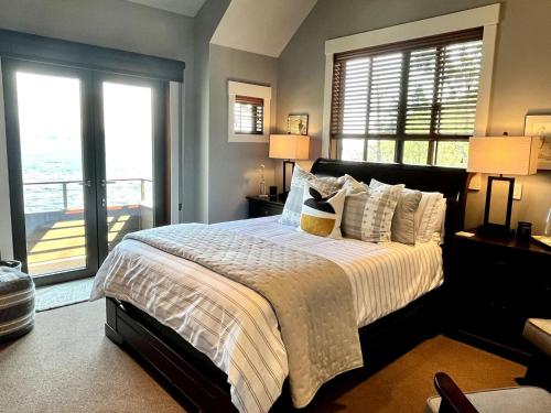 a bedroom with a large bed with two windows at Ideal Beachfront Retreat Experience Gorgeous! in Friday Harbor