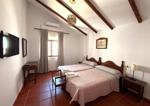 a bedroom with two beds and a television in it at Hotel Rural Palacete de Mañara in Montejaque