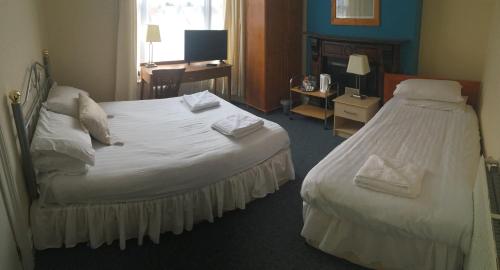 Cette chambre comprend un grand lit blanc et un bureau. dans l'établissement Four Seasons Budget, à Aberystwyth