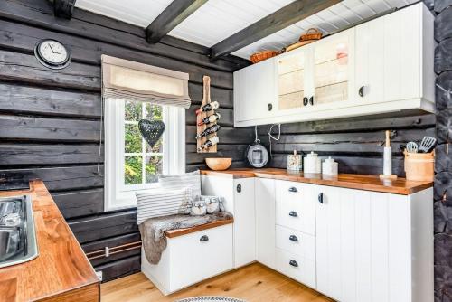 eine Küche mit weißen Schränken und einer Holzwand in der Unterkunft Family-Friendly Log Cabin With Panoramic View in Østby