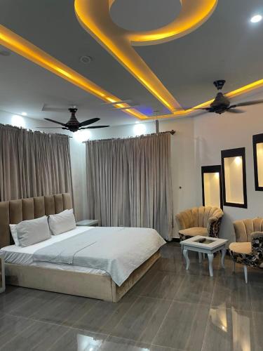 a bedroom with a large bed and two chairs at Comfort Family Lodges in Islamabad