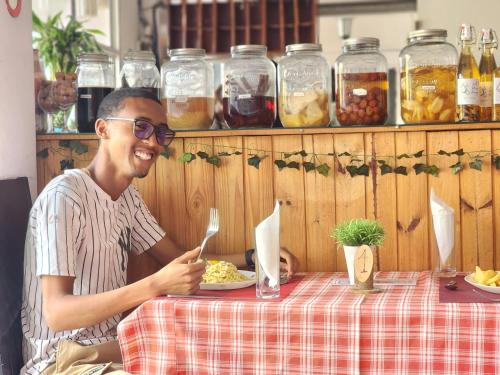 a man sitting at a table with a plate of food at La Casa Di Luna - Hotel with Pool and Restaurant in Antananarivo in Antananarivo