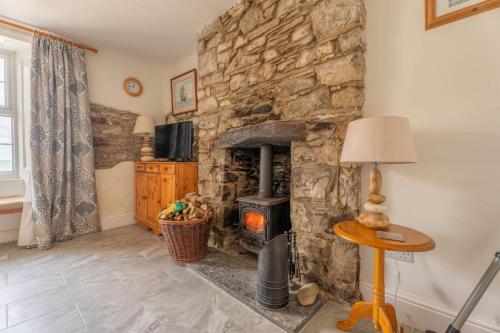 a stone fireplace in a living room with a stove at Trem y Don at Llangrannog Beach in Llangrannog