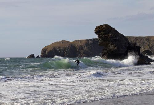 a man riding a wave on a surfboard in the ocean at Trem y Don at Llangrannog Beach in Llangrannog