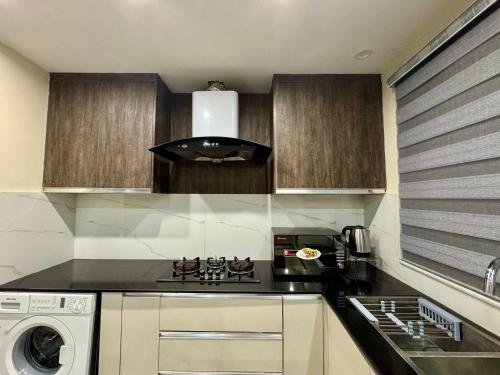 a kitchen with a stove top oven next to a washing machine at Lux Haven Stays 2 Bedroom Luxury Apartment Near Gulberg - Ultimate Getaway Experience in Lahore