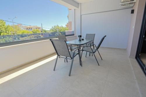 a table and chairs on a balcony with a window at Isol Rooms A1 in Katerini