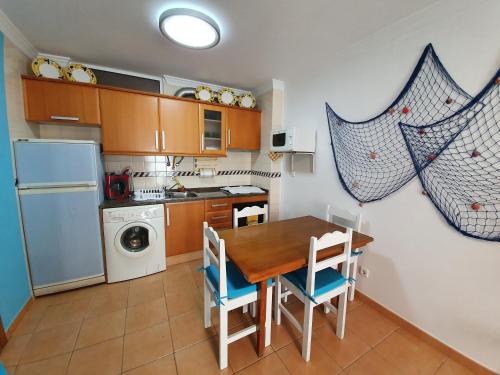 a kitchen with a table and chairs and a refrigerator at Casa T2 in Monte Gordo