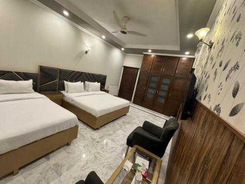 a hotel room with two beds and a chair at Comfort Family Lodges in Islamabad