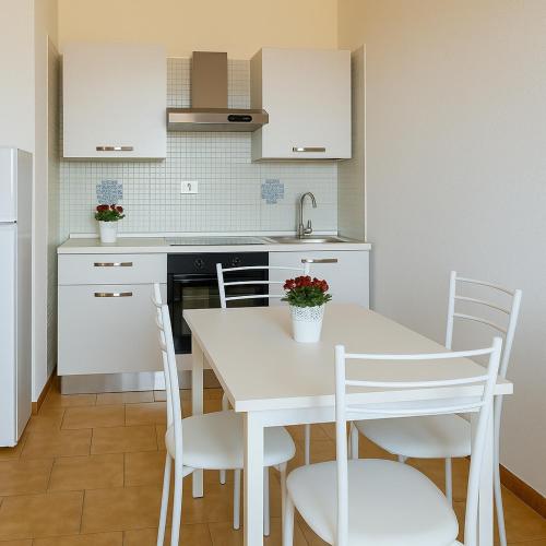 a white kitchen with a white table and chairs at Vulcanello Sea View Apartment in La Fabbrica