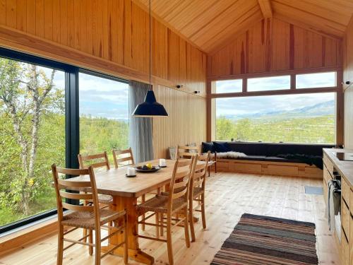 a dining room with a table and chairs and large windows at Architectural Gem With Views Of Hallingskarvet in Ustaoset