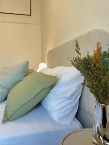 a bed with pillows and a vase with flowers on it at OverGarden Rooms in Dossobuono