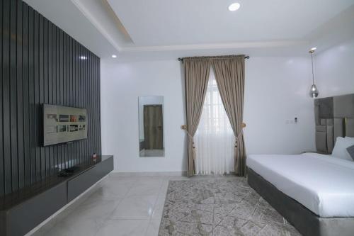 a white bedroom with a bed and a window at Fort Fountain Apartments in Abuja