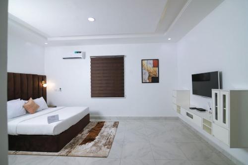 a white bedroom with a bed and a television at Fort Fountain Apartments in Abuja