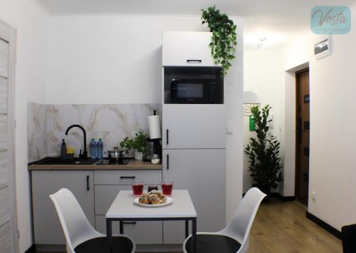 a kitchen with a table and chairs and a refrigerator at VESTA Apartamenty M52 Free parking in Szczecin