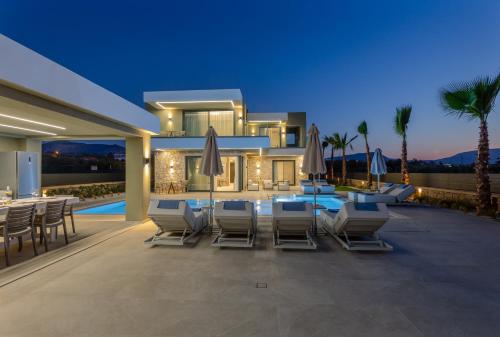 a house with a patio with chairs and a pool at Divel Luxury Villas with heated pools, by Estia in Anissaras