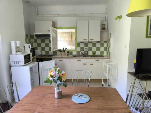 a kitchen with a table with a vase of flowers on it at Résidence les Sources in Prats-de-Mollo-la-Preste