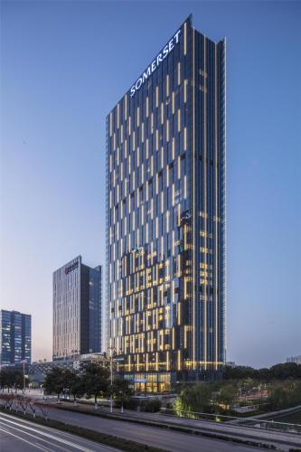 a tall building with many windows next to a highway at Somerset Baitang Suzhou in Suzhou
