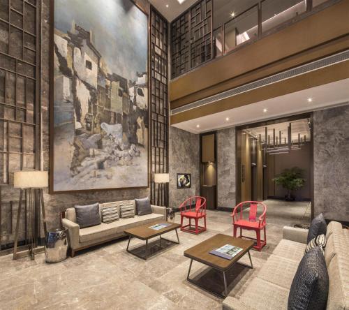 a lobby with a couch and two red chairs at Somerset Swan Lake Hefei in Hefei