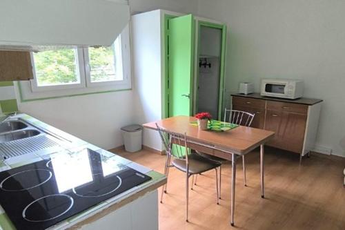 a kitchen with a table and a green door at Résidence les Sources in Prats-de-Mollo-la-Preste