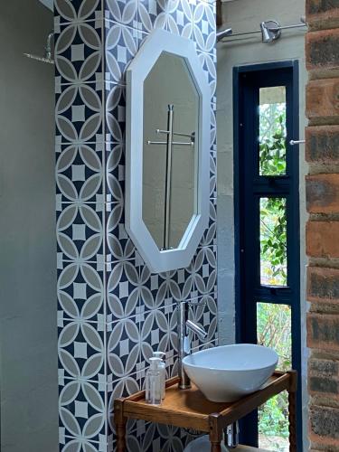 a bathroom with a sink and a mirror on a wall at Rosetta River Retreat in Mooiriver