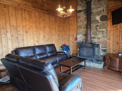 a living room with a leather couch and a fireplace at 3BR Panoramic Lake View, Sequoia Forest, Kern County in Wofford Heights
