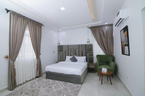 a bedroom with a bed and a green chair at Fort Fountain Apartments in Abuja