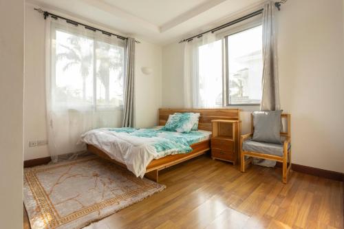 ein Schlafzimmer mit einem Bett und einem Stuhl und einem Fenster in der Unterkunft Serenity Shores in Daressalam