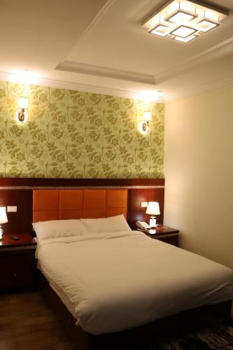 une chambre avec un grand lit et deux tables de nuit dans l'établissement Tilman Hotel, à Addis-Abeba