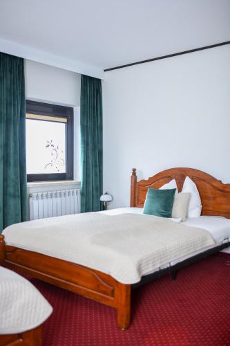 a bedroom with a large wooden bed with a window at Hotel Zodiak in Radomsko