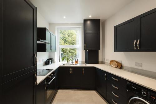 a kitchen with black cabinets and a window at Luxury 3 Bed Home Near Peak District with Cinema Room in Mossley