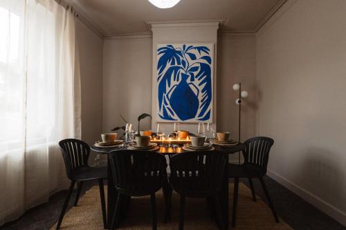 a dining room table with chairs and a blue and white painting at Luxury 3 Bed Home Near Peak District with Cinema Room in Mossley