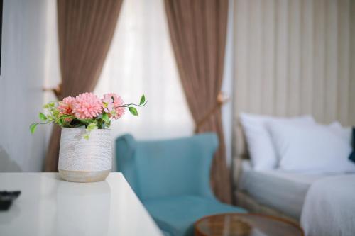 a vase with pink flowers on a table in a hotel room at Fort Fountain Apartments in Abuja