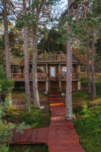 a log home in the woods with a pathway leading to it at Metskapteni Puhkemaja in Põõsaspea