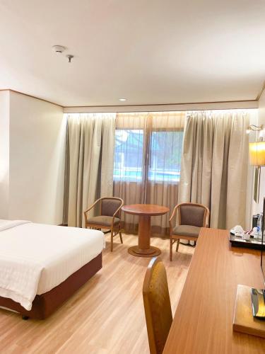 a bedroom with a bed and a table and chairs at Sima Thani Hotel in Nakhon Ratchasima
