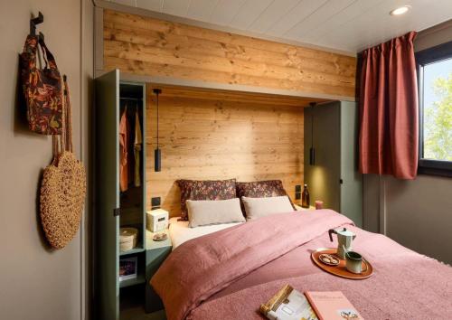 una camera da letto con un letto grande con una parete in legno di Résidence Camping La Buidonniere - Chalet confortable et lumineux en pleine nature MAE-1033 ad Aussois