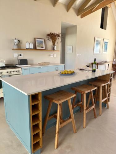 a kitchen with a large island with wooden stools at Sandown Synergy Lagoon House in Hermanus